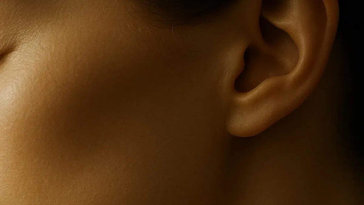 Close macro of a cheek, jawline and ear in warm gold light, the midface area an 8 point facelift treats