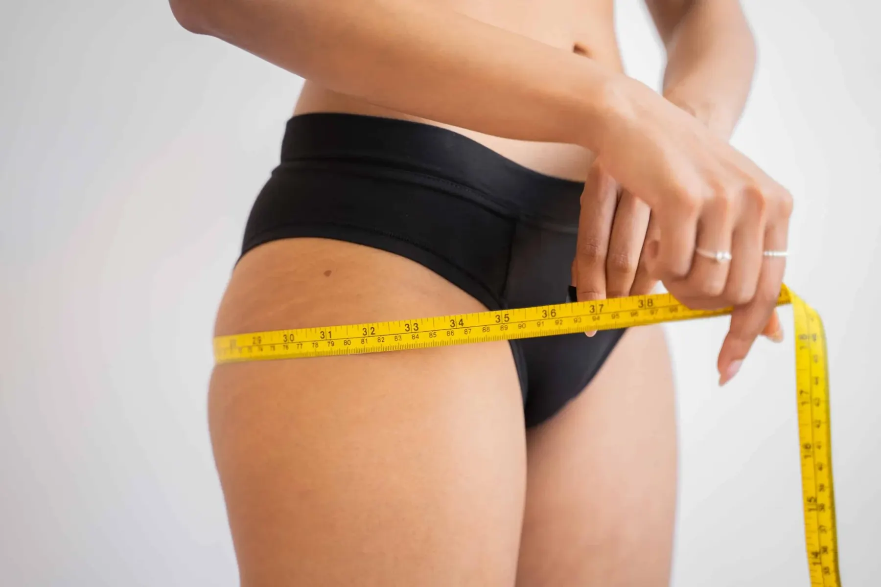 Woman measuring her thigh with tape