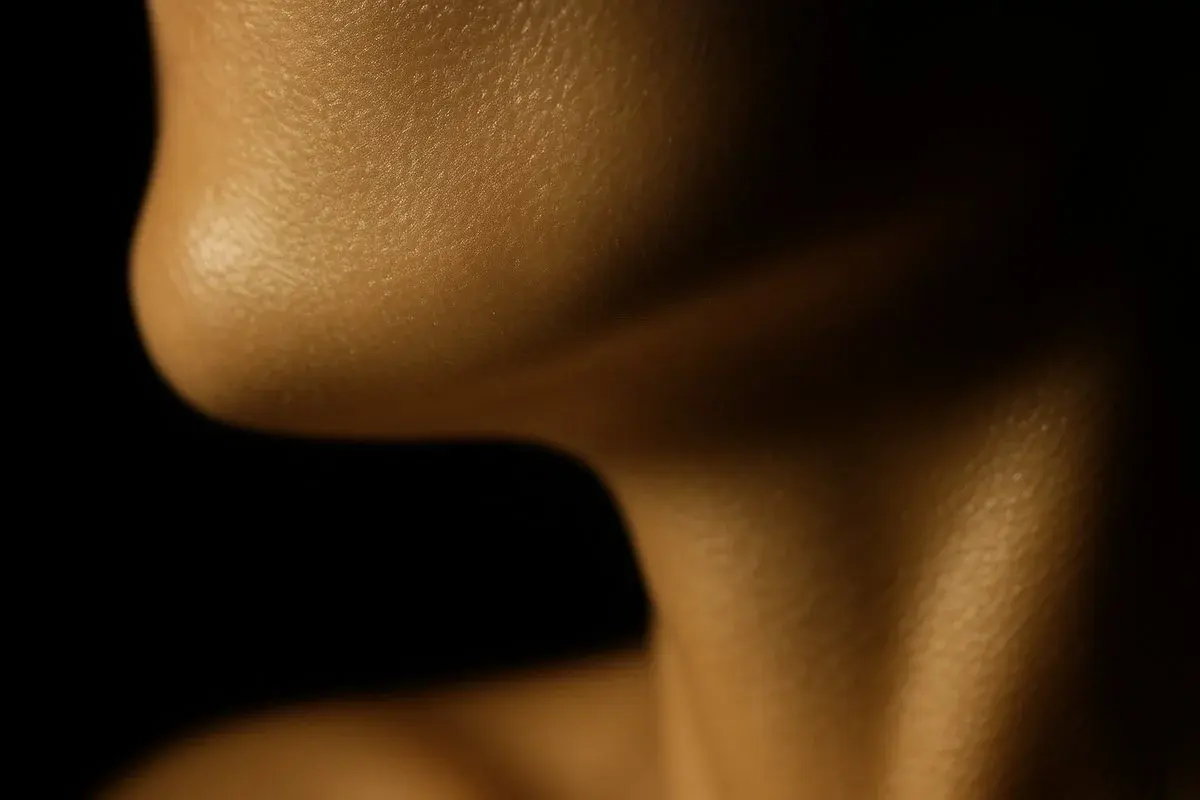 Close up editorial photograph of a defined jawline and neck in warm gold light, illustrating the lower face contour masseter Botox refines at Luxe Skin Glasgow